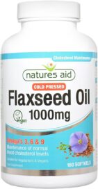 Bottle of Natures Aid Cold Pressed Flaxseed Oil capsules on a bed of flaxseeds.